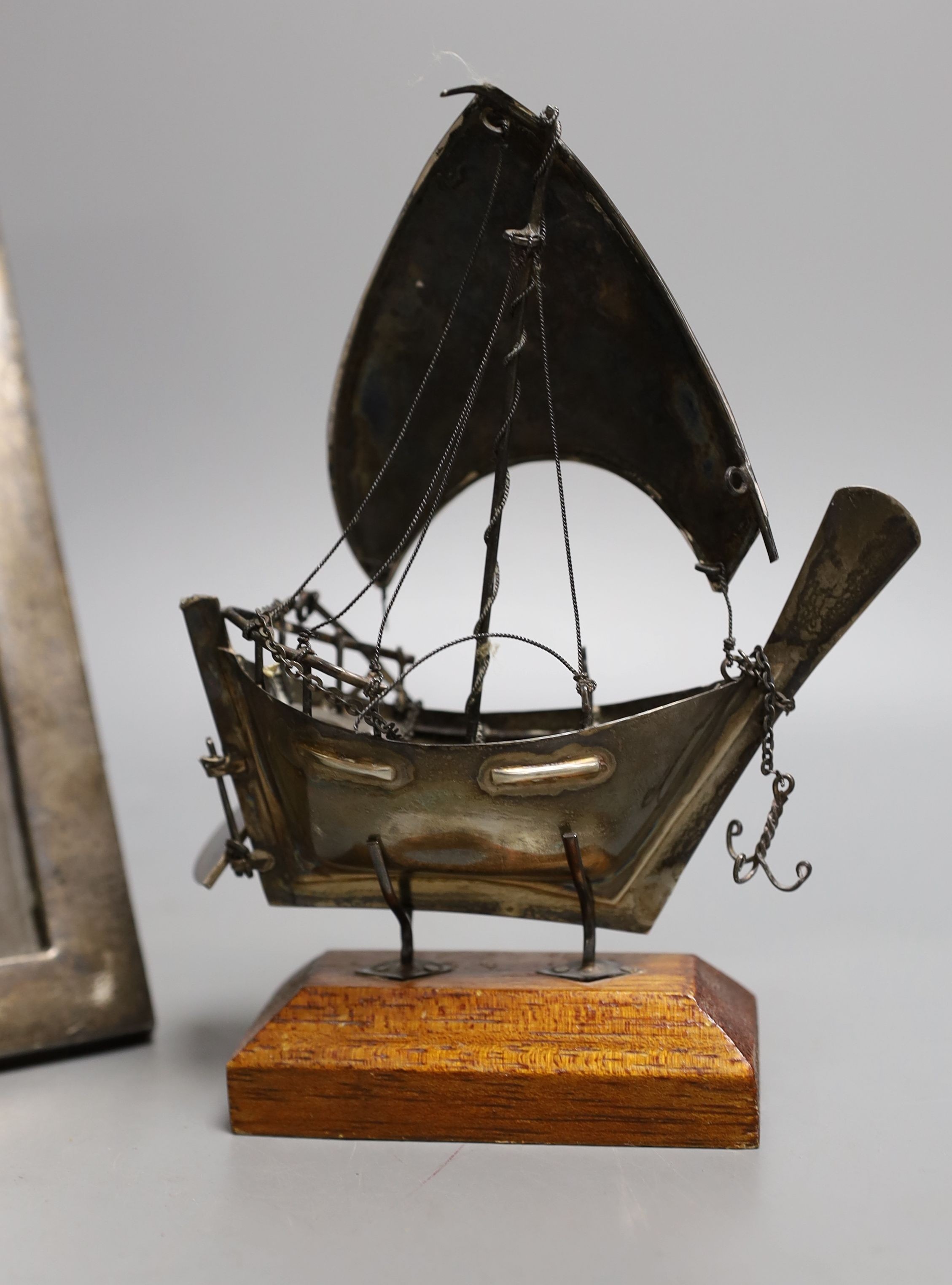 A George V silver mounted rectangular photograph frame, 24.2cm, a 1930's silver trinket box and a miniature white metal model of a sail boat, on wooden stand.